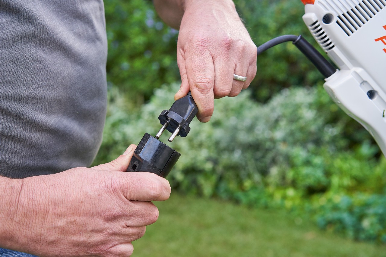 A man wearing protective gloves actuating the trigger of the STIHL FSE 60 electric brushcutter to start it