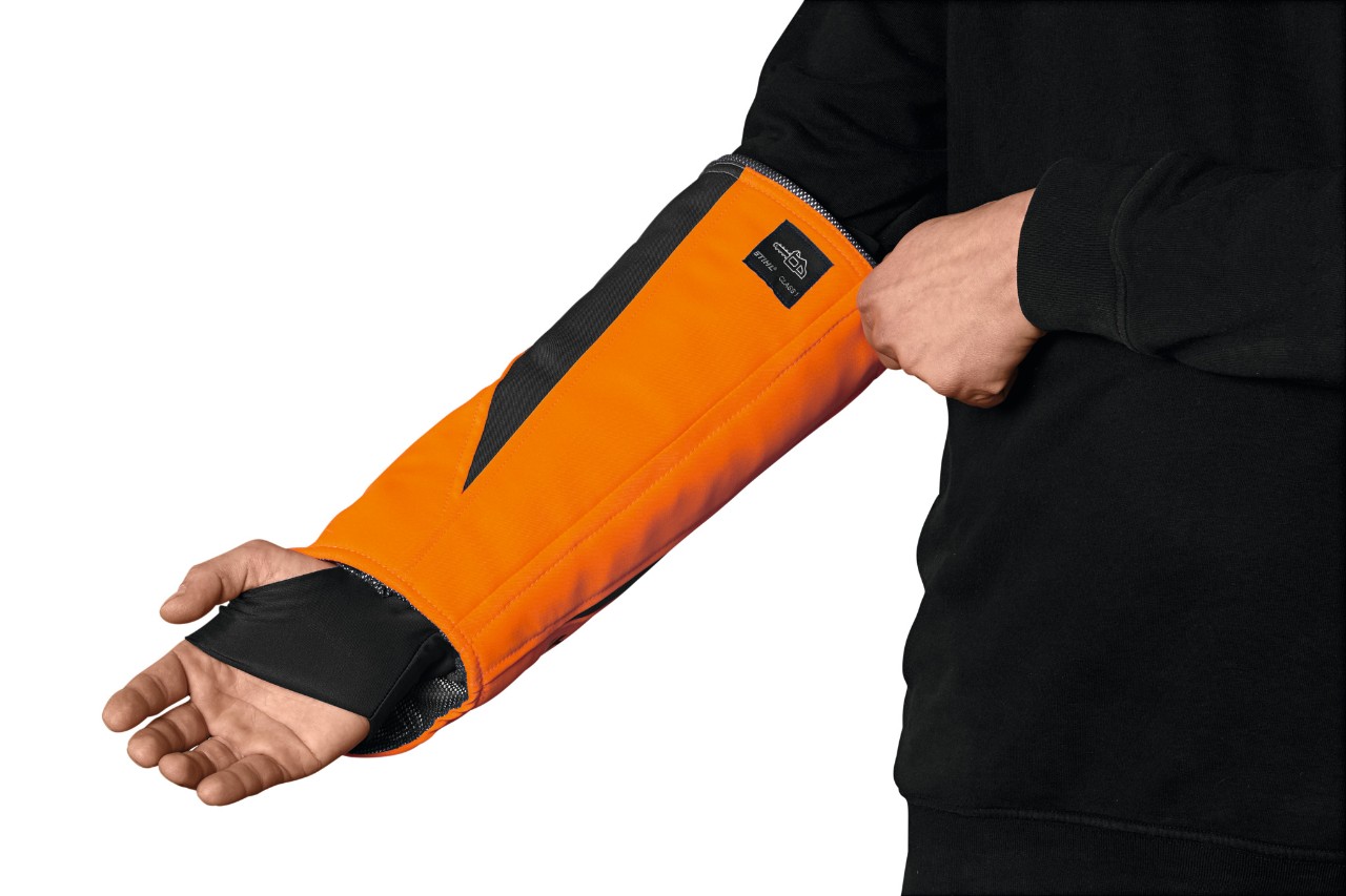 A forestry worker wearing STIHL Protect MS protective clothing, standing on a work platform using a chainsaw on a tree